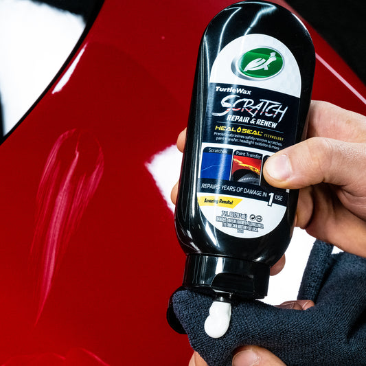 Red car panel with Turtle Wax Scratch Repair. Detailer applying formula to cloth for car paint scratch removal.