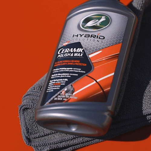 Turtle Wax Hybrid Solutions Ceramic Polish & Wax. A 500ml bottle of car detailing product against a red background with a grey microfibre cloth.