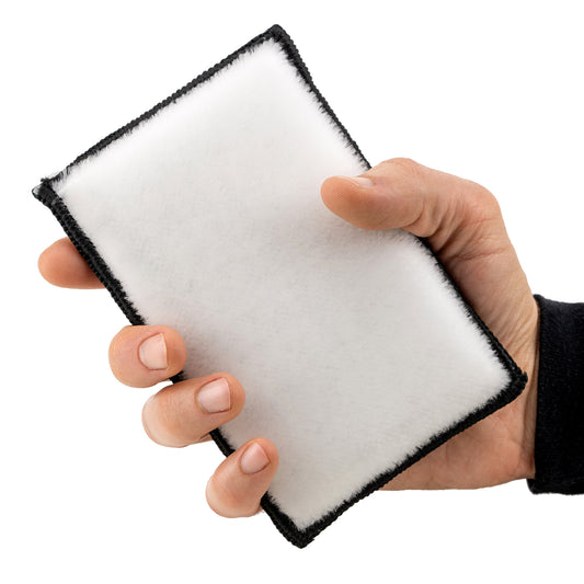 Hand gripping a white, microfibre interior detailing applicator with black trim. Ideal for cleaning auto interiors.