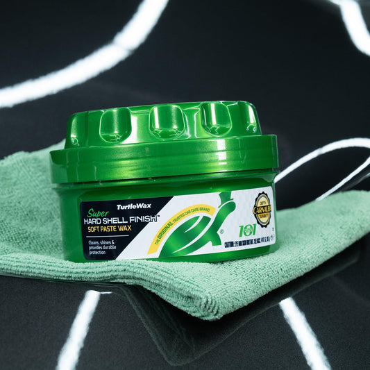 Turtle Wax hard shell finish paste wax in a green container on a microfibre cloth. Car care product on a car's glossy surface.