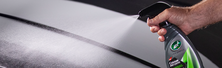 Man spraying turtle wax ceramic spray costing onto a vehicle