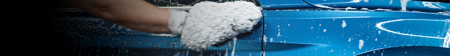 Man washing a blue car with a pH neutral wash