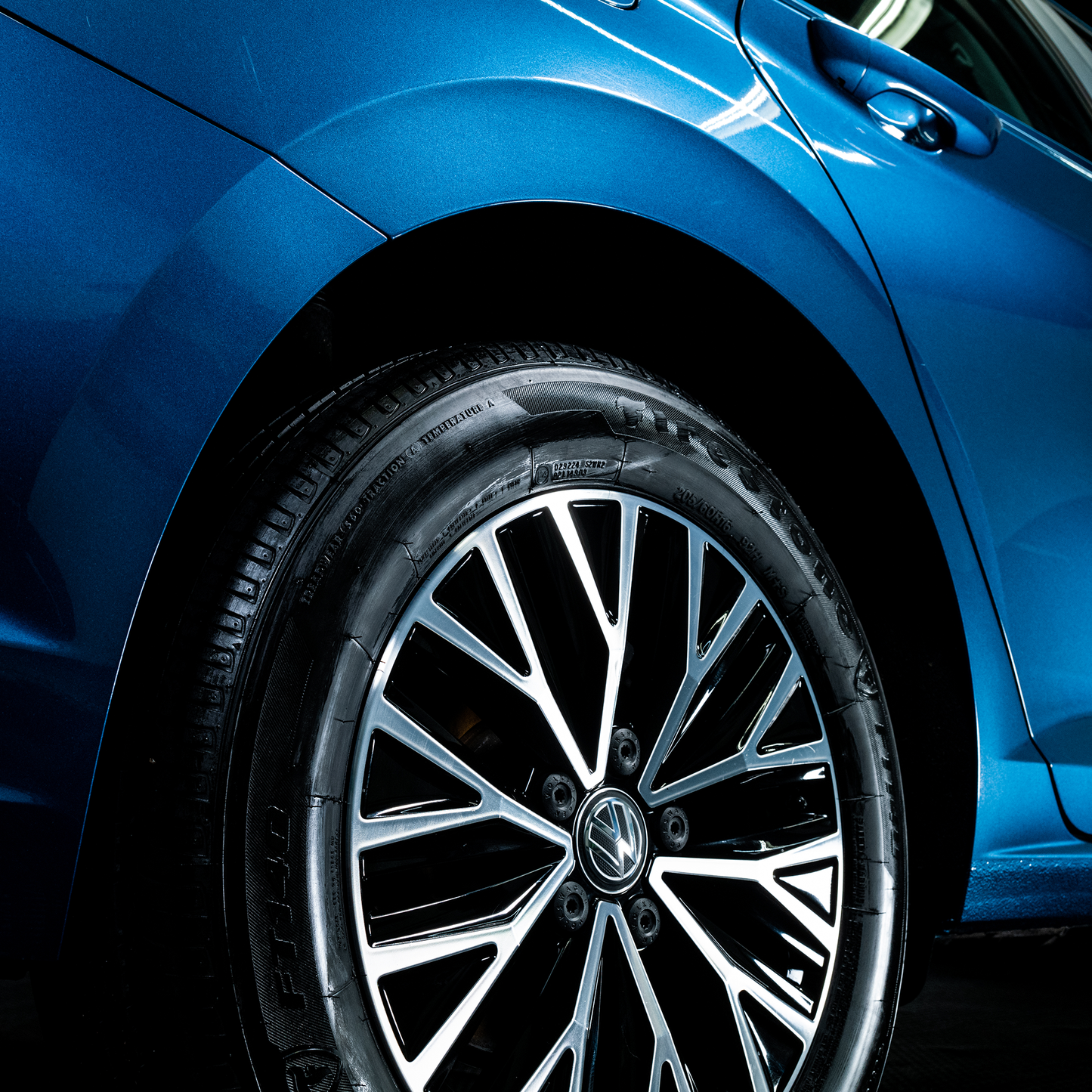 Shiny, blue car with alloy wheels and wet tyres. Freshly cleaned.
