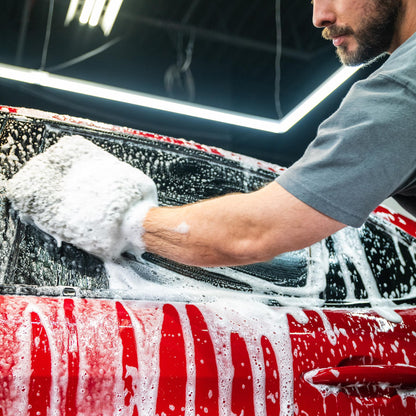 Man washing a red car with a foamy mitt. Car cleaning and detailing.