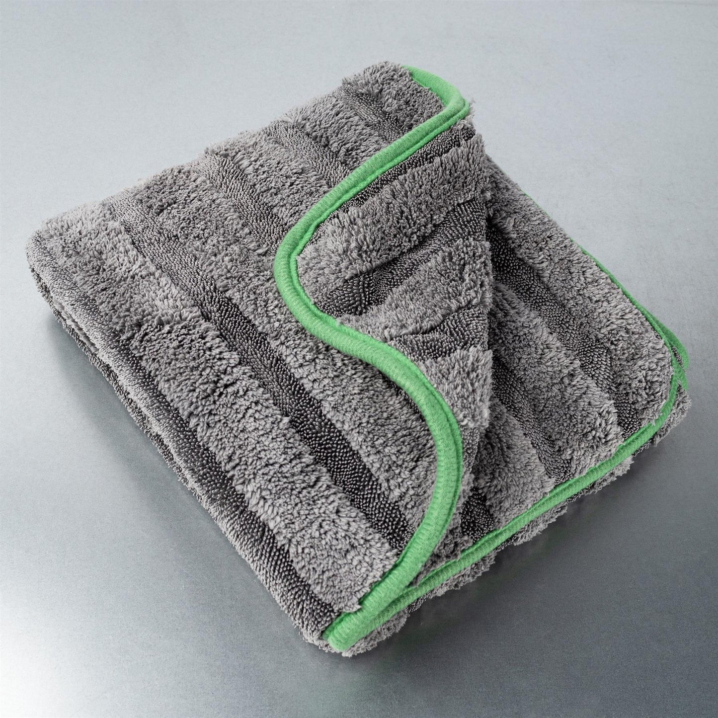 Grey, stripey, fluffy microfibre drying towel with a green edge. Car care item.