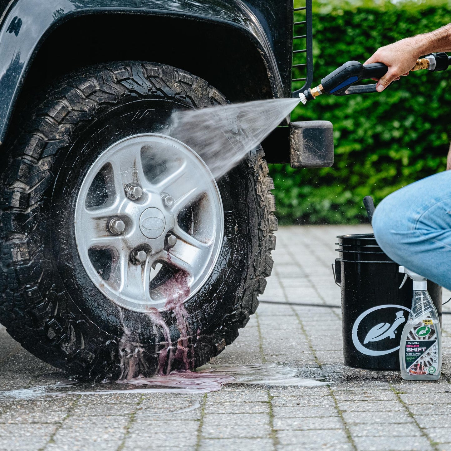 Cleaning a 4x4 wheel with Turtle Wax Color Shift. Red residue shows product working. Tyre and alloy detail.
