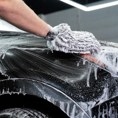 Soapy car wash. Hand cleaning black vehicle bodywork using a mitt. Automotive detailing and valeting service.