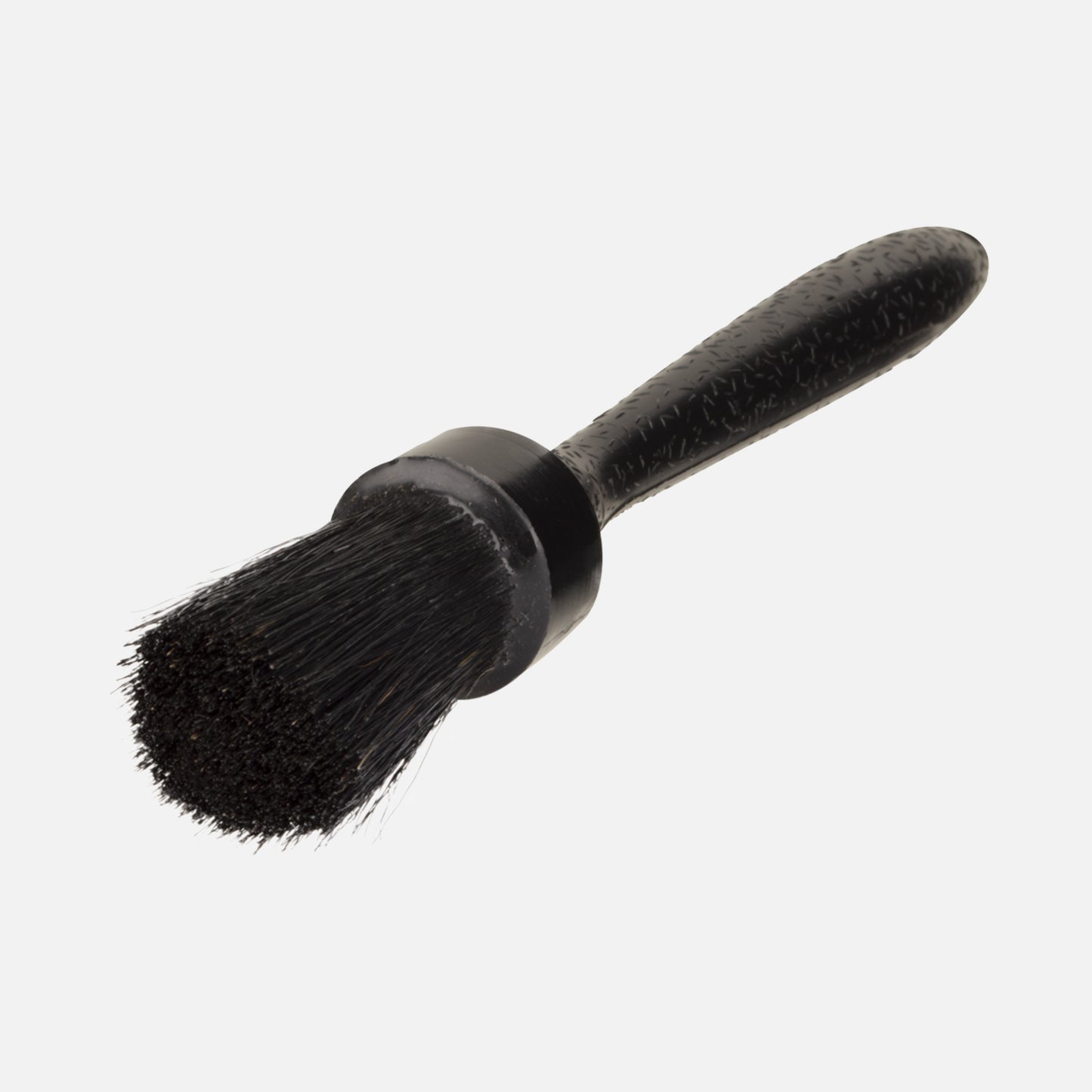 Close-up of a detailing brush with dark bristles and a textured black handle for vehicle care.