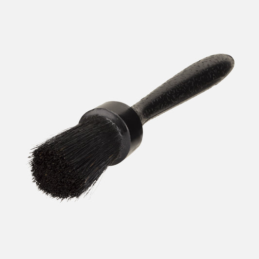 Close-up of a detailing brush with dark bristles and a textured black handle for vehicle care.