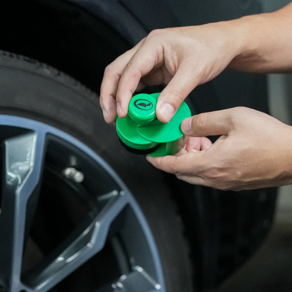 Applying tyre shine with a Turtle Wax applicator. A green detailing tool is shown to give car tyres a brilliant finish.