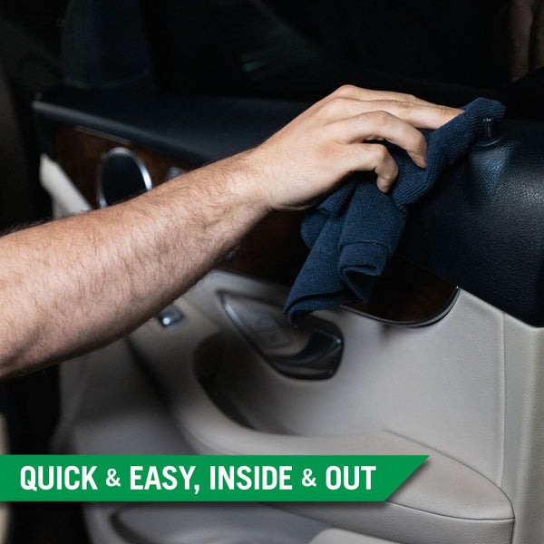 A hand using a black microfibre towel to wipe the black plastic trim on the inside of a cars door frame. 