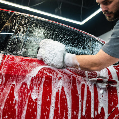 Red car getting a foamy Turtle Wax wash. Hand detailing for a gleaming finish.