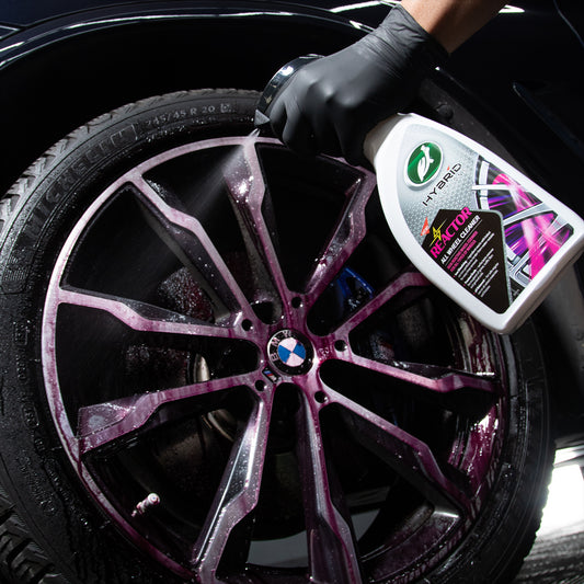 BMW alloy wheel being sprayed with Turtle Wax Hybrid Solutions Reactor cleaner. Purple residue shows reaction with brake dust.