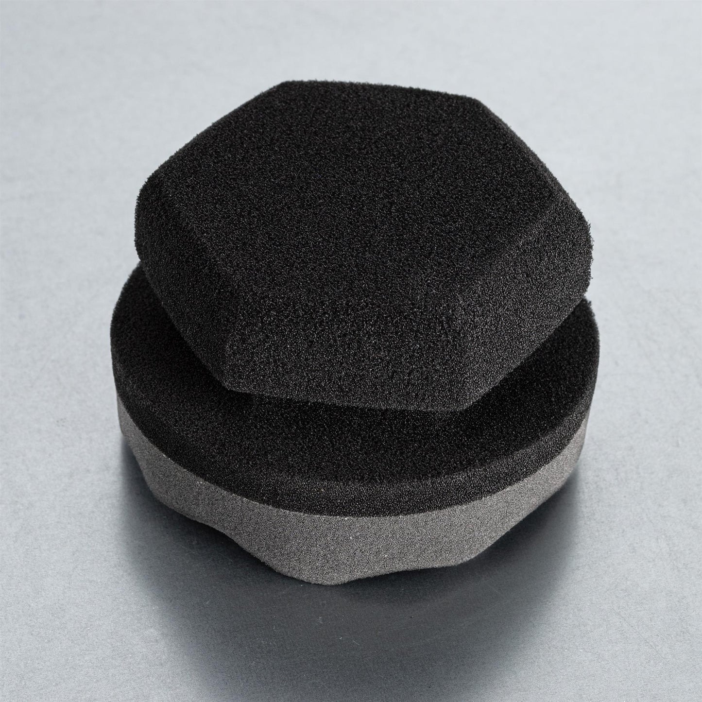 Car detailing: stacked foam applicators. One hexagon-shaped, the other round with grey side.