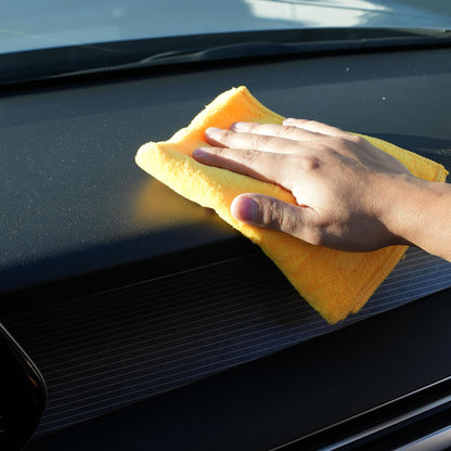 Hand using a yellow microfiber cloth to clean a car's black surface