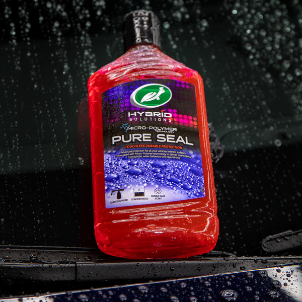 Pure Seal is placed leaning up against the windshield of a car with water beading all around the product. 