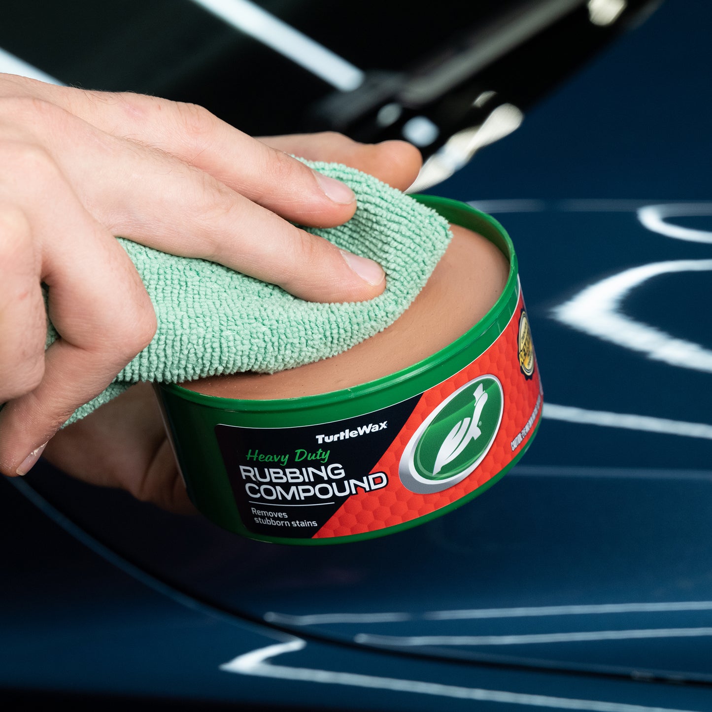 Turtle Wax heavy-duty rubbing compound. Car detailing, removing stubborn stains with a cloth. Vehicle cleaning product.