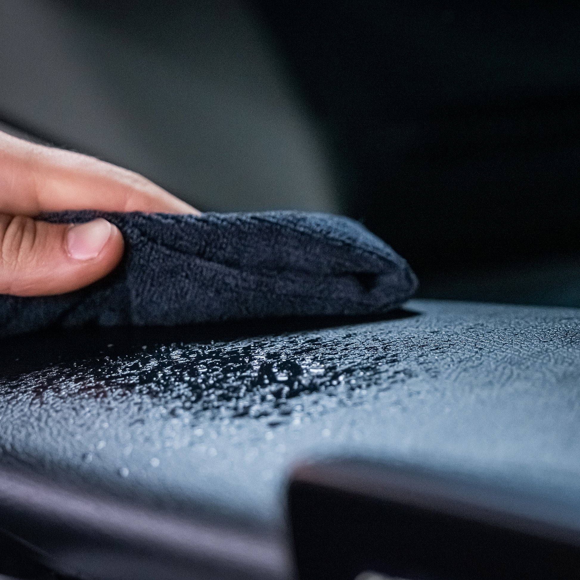 Cloth wiping wet dash. Car interior detailing for a streak-free finish. Cleaning product usage.
