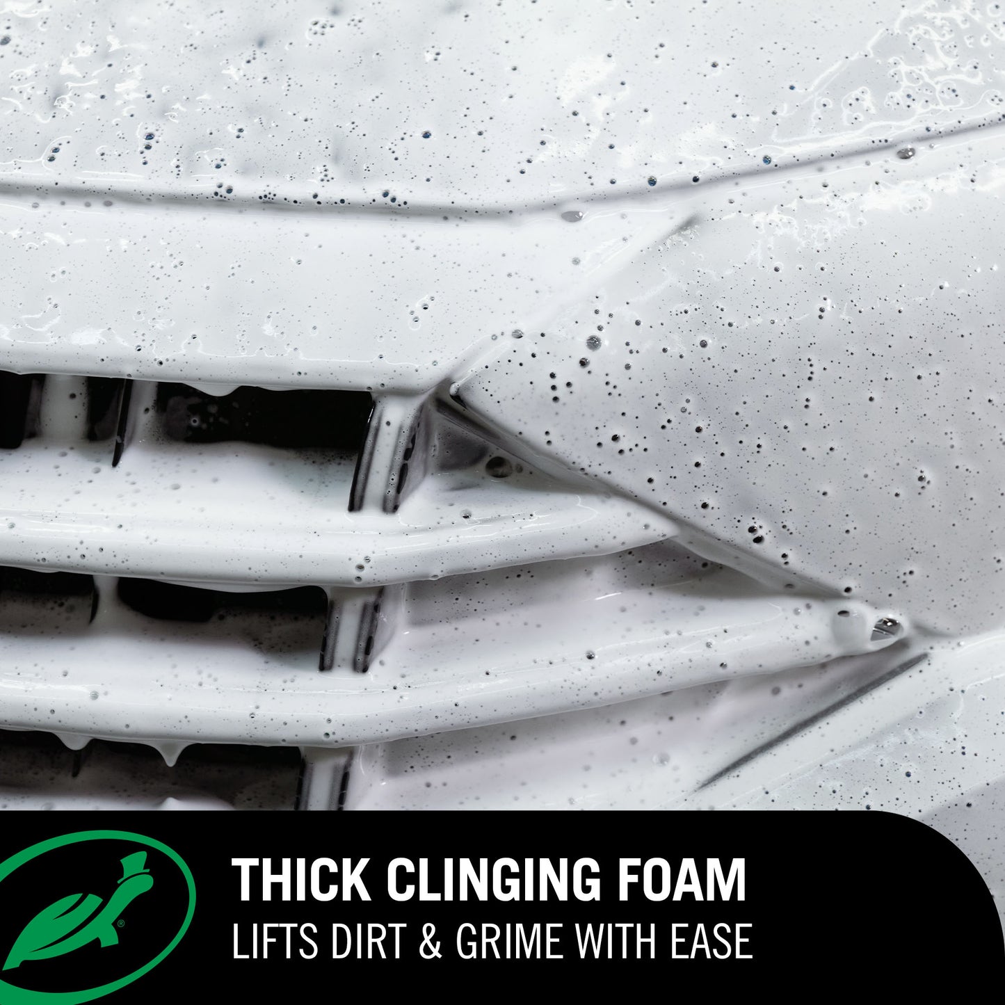Car grill with concentrated snow foam applied, lifting dirt and grime.