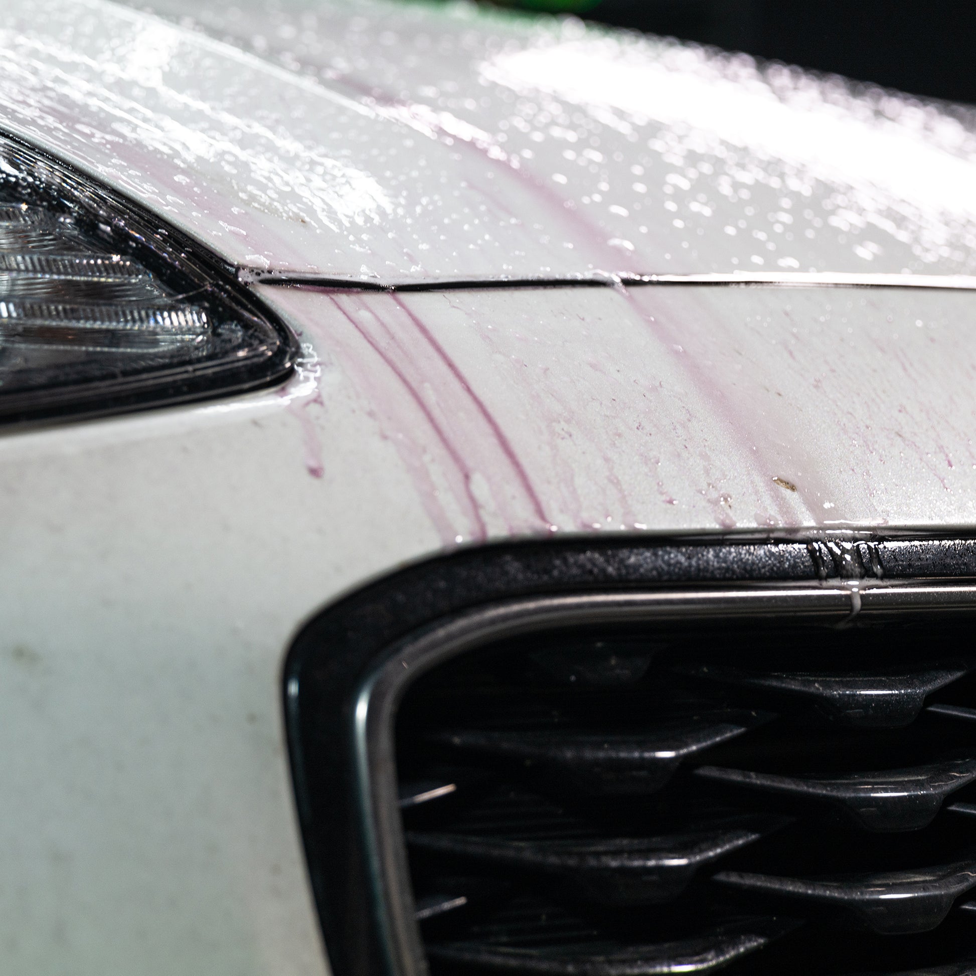 Car detailing: white vehicle close-up with red iron contamination streaks being removed, Turtle Wax.