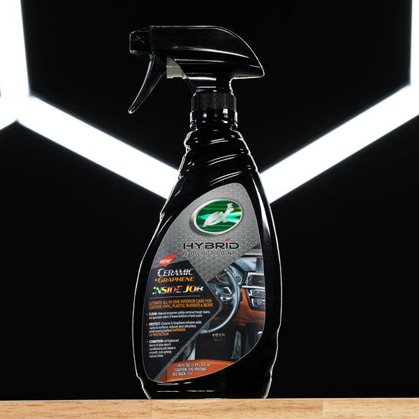 Close-up of hands wiping a black dashboard with a microfiber cloth using HS Ceramic Graphene Inside Job, showing a clean matte finish on the surface.