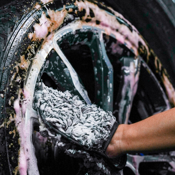Close-up of a car wheel being cleaned with a microfibre mitt, creating soapy lather. Ideal for car valeting & detailing.