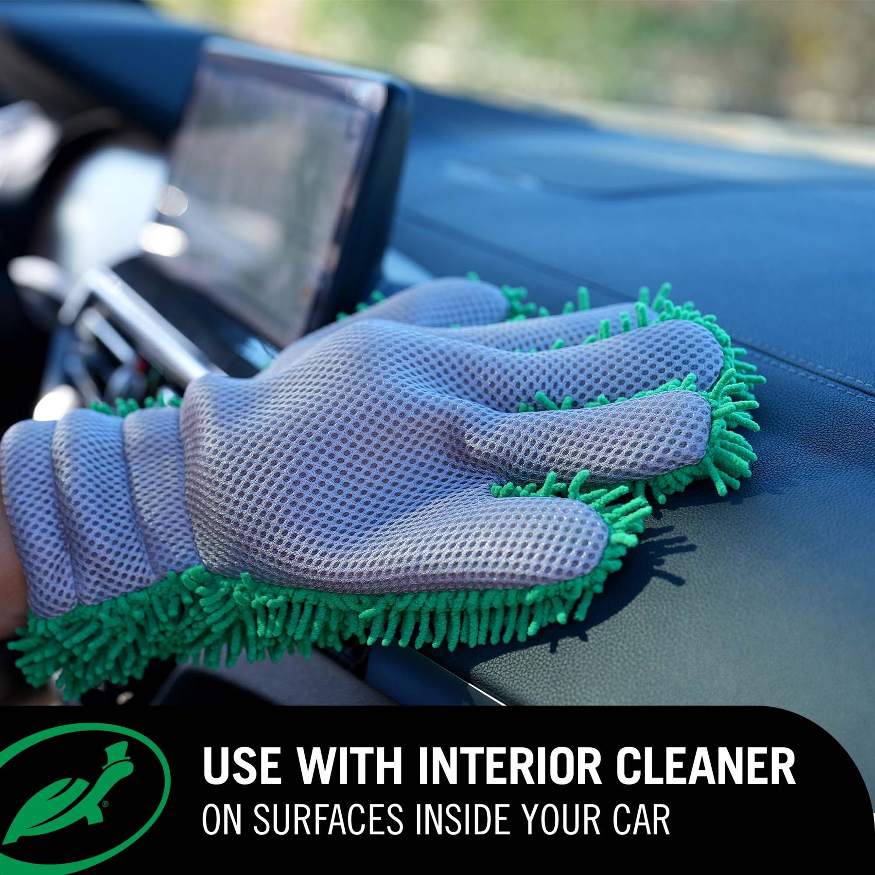 Gray cleaning glove with green bristles cleaning a car interior.