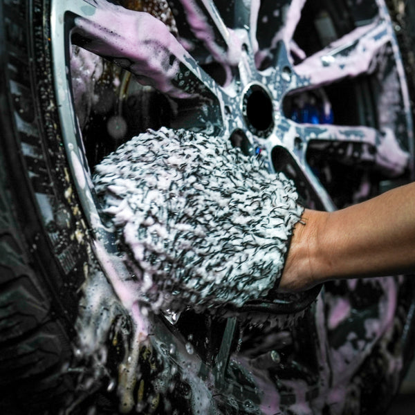 Cleaning car wheels with a microfibre mitt and soapy water. Car detailing and valeting imagery.
