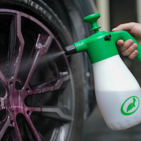 Turtle Wax foaming spray device being used on a car wheel. The device is green and white. Car care and detailing supplies.
