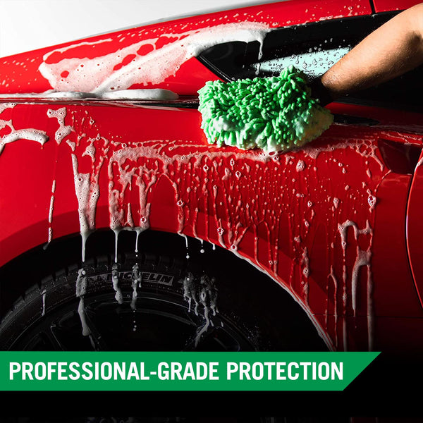 Detail shot of a hand applying wax to a red car panel using a yellow foam applicator pad.