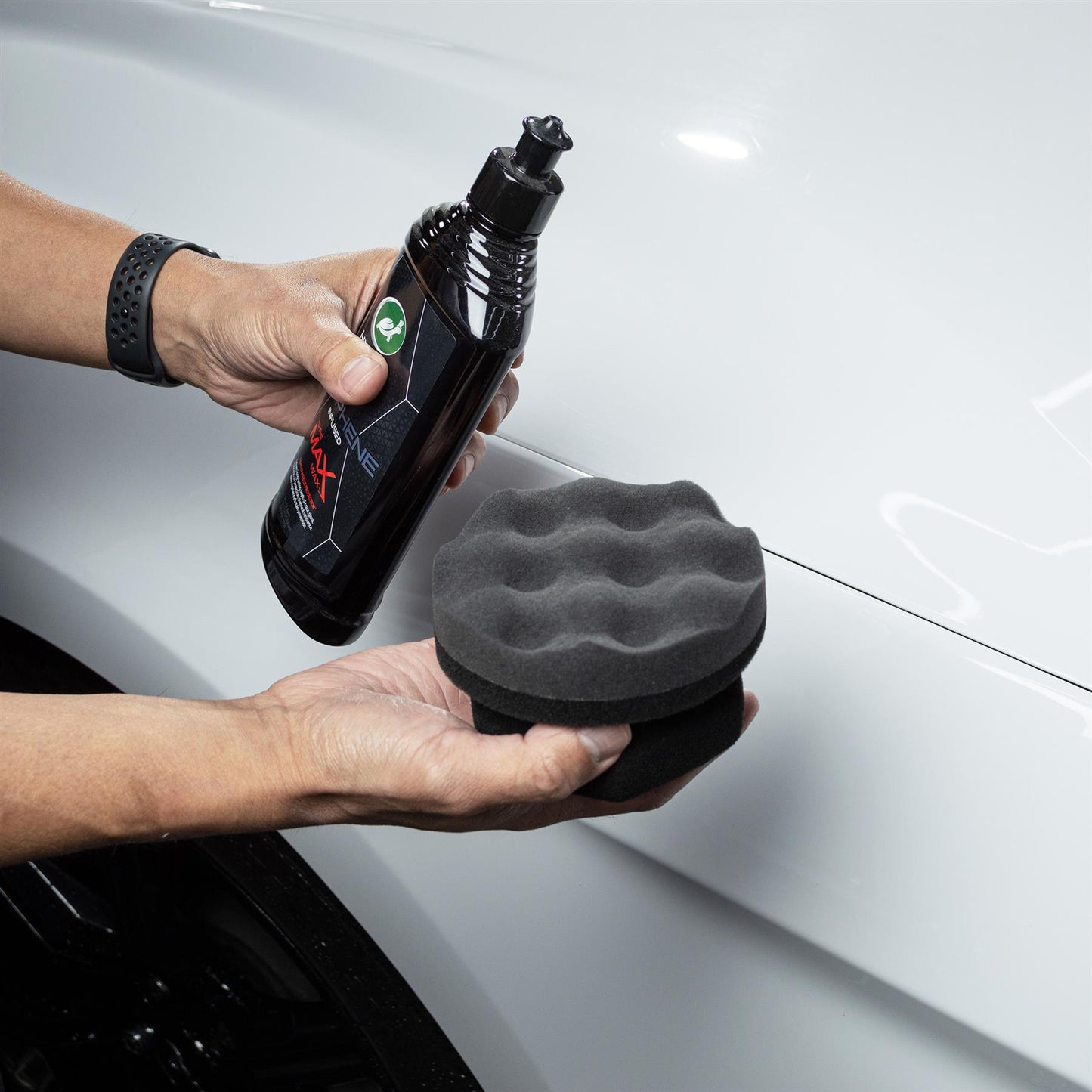 Hands prep a car's surface with Turtle Wax Graphene infused polish and a foam applicator for a professional-grade sheen.
