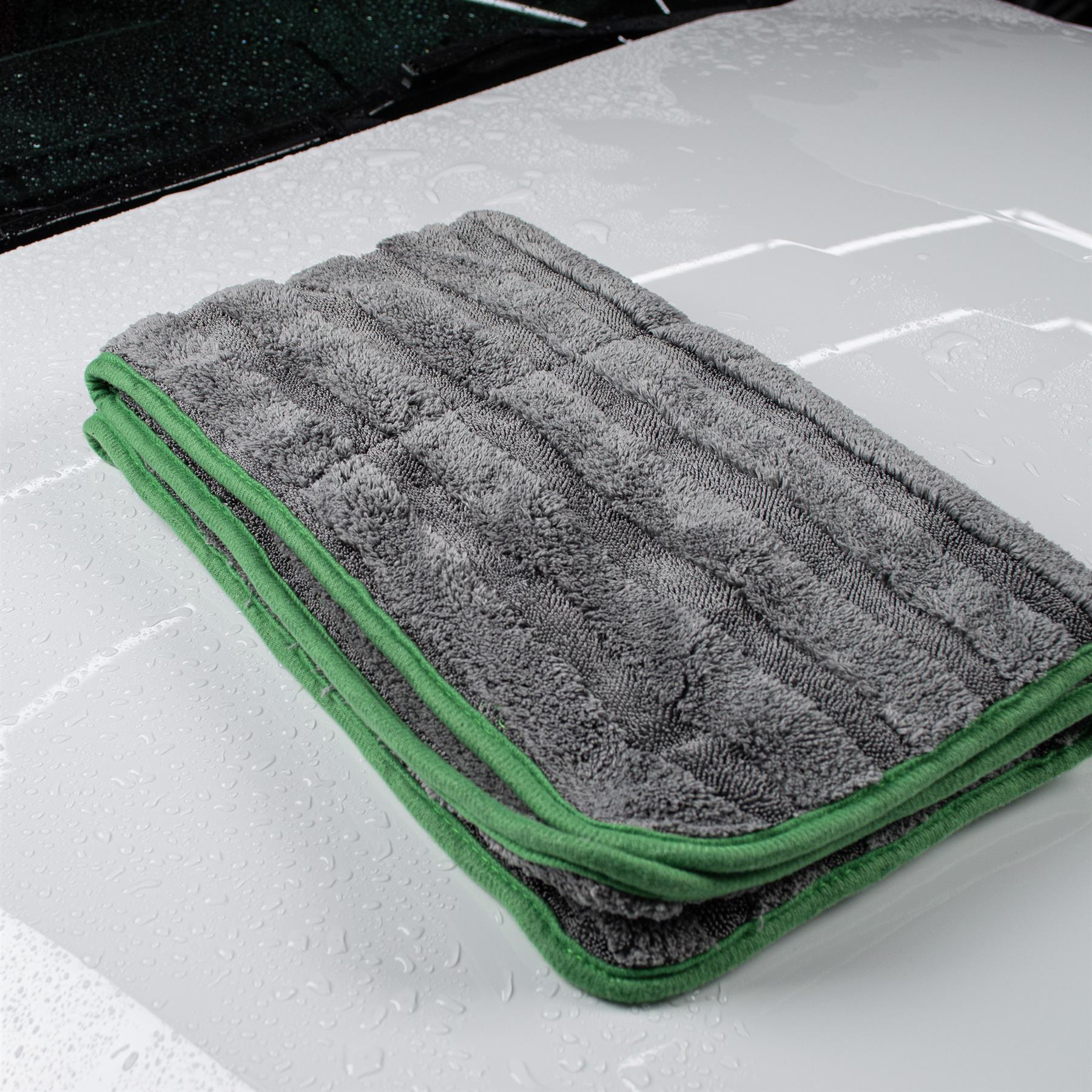 Grey Turtle Wax drying towel, with green edging, sits on a wet, clean car bonnet.