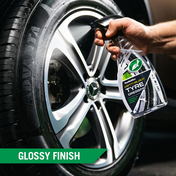 A hand using an applicator pad to apply Wet'n Black Tyre Dressing to the tyre of a car, highlighting the high gloss finish of the product.