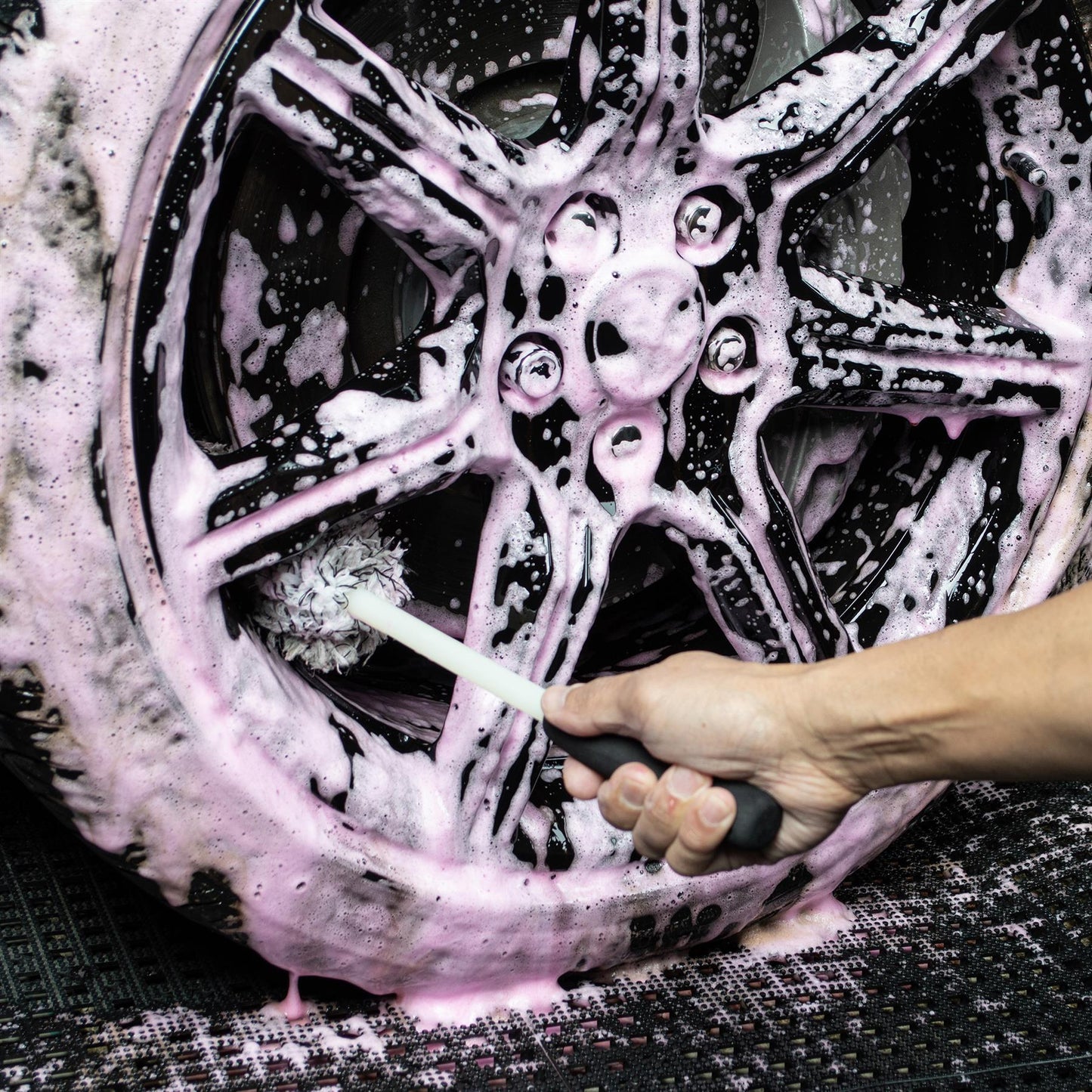 Cleaning alloy wheels with a detailing brush and soapy pink solution. Car care and valeting.
