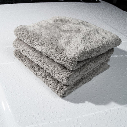 Stack of plush microfibre cloths on a wet white car bonnet. Ideal for Turtle Wax car care.
