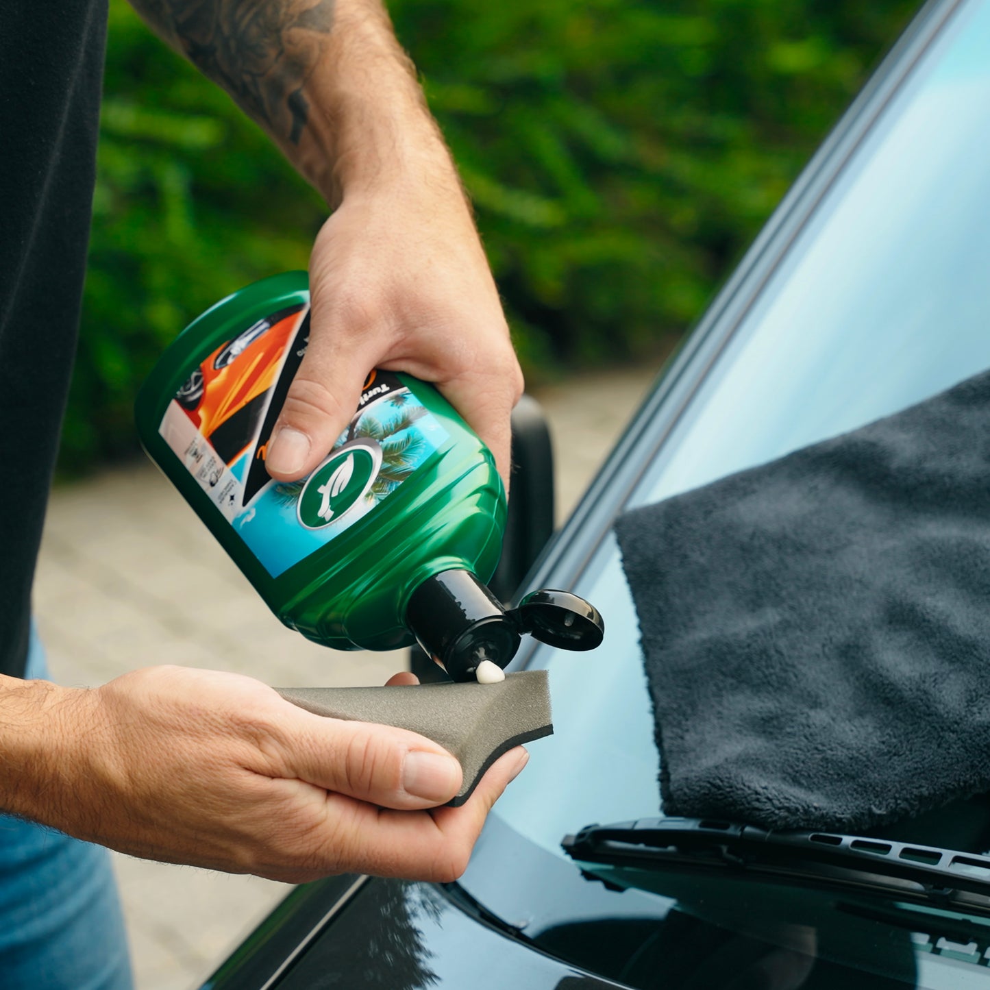 Applying Turtle Wax carnauba wax polish to an applicator sponge before use on a car.