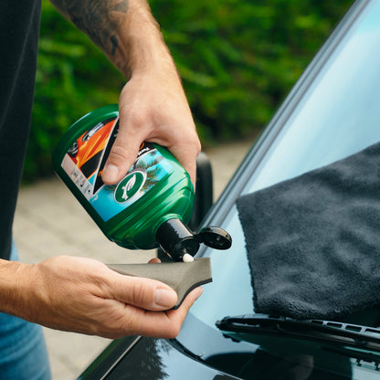 Applying Turtle Wax carnauba wax polish to an applicator sponge before use on a car.