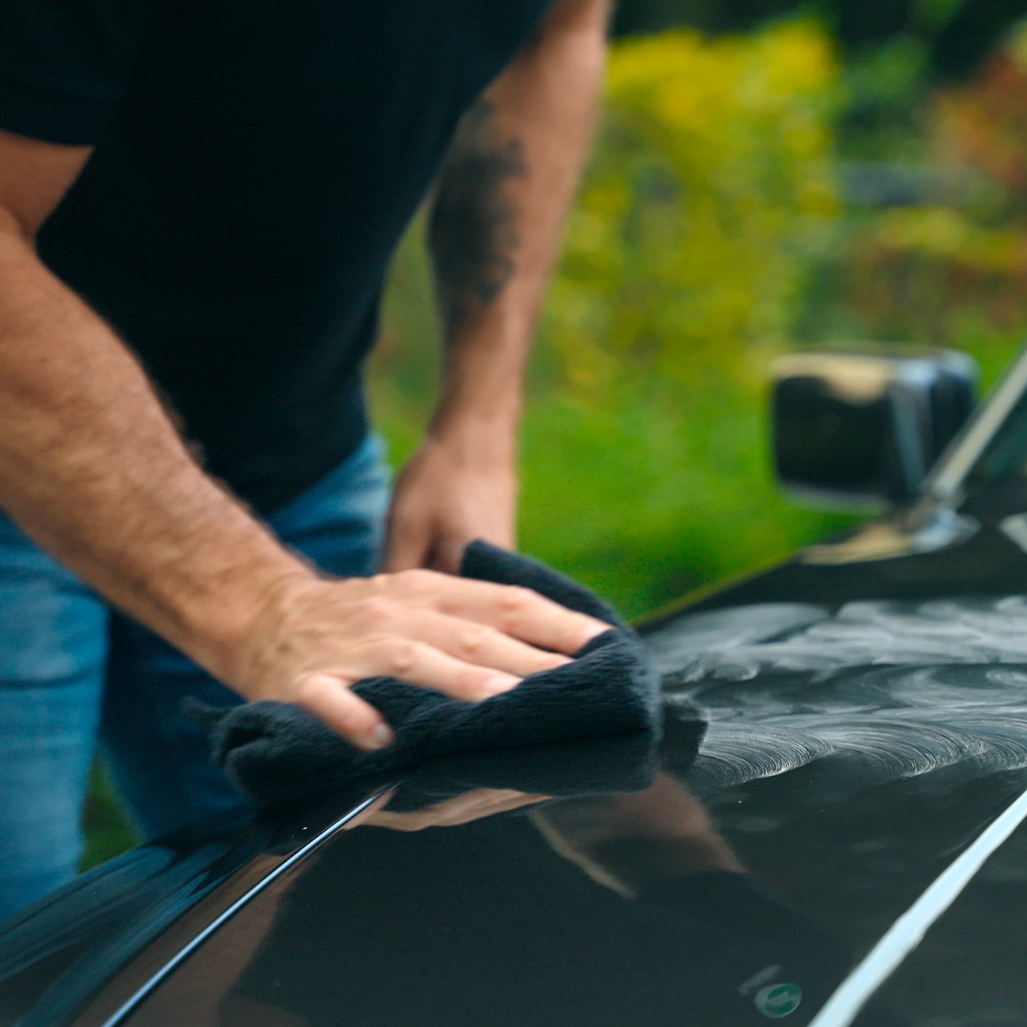 Detailing a car. Man polishing black vehicle with cloth. Turtle Wax.
