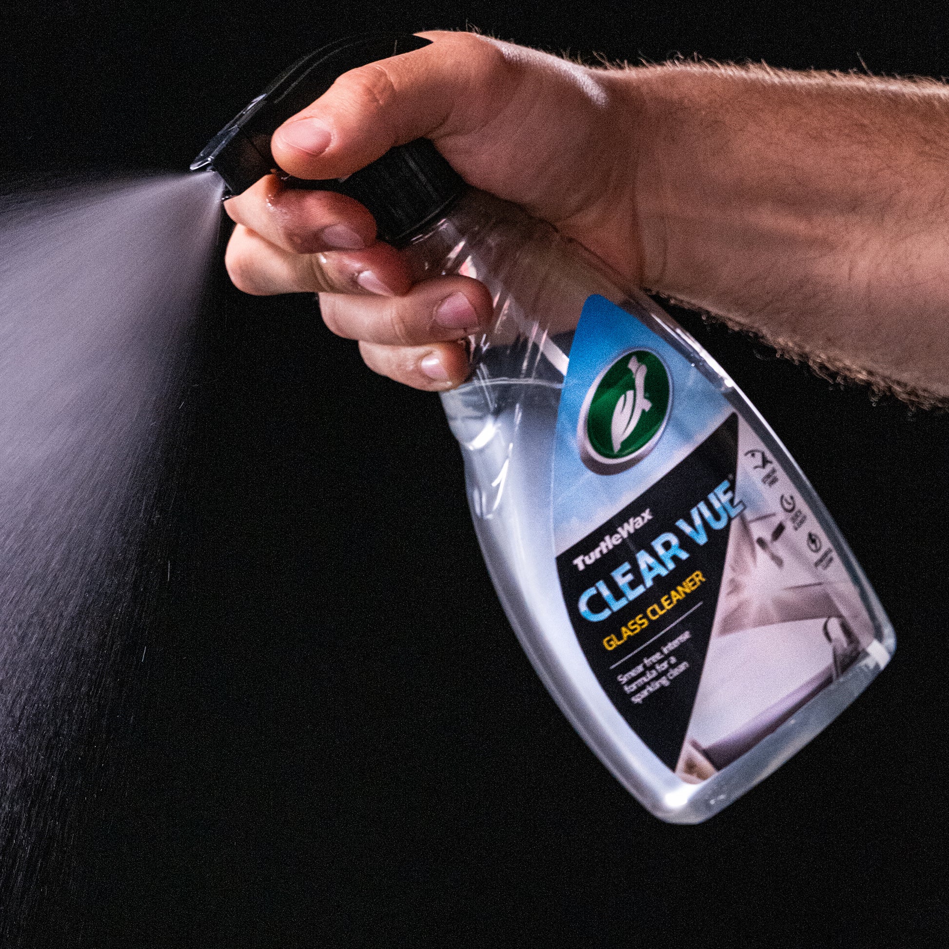 Hand spraying Turtle Wax Clear Vue Glass Cleaner. Car care product for a smear-free, intense clean.