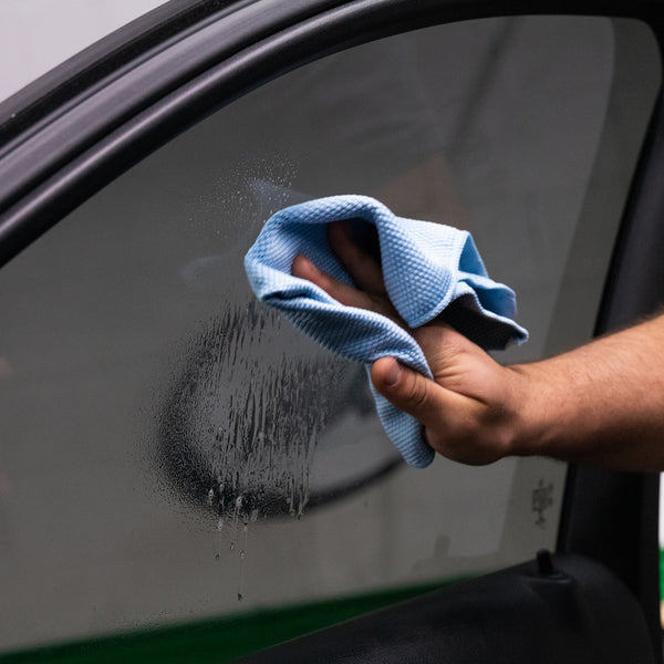 Side view of Clear-Vue Glass Cleaner being used on a window, showing streak-free clarity and a hand with cloth.