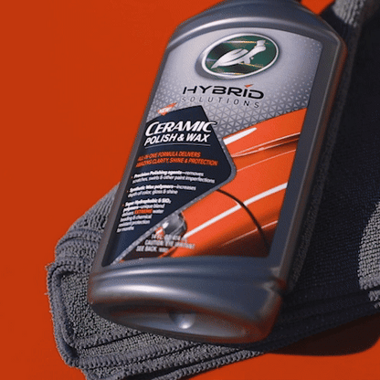 Turtle Wax Hybrid Solutions Ceramic Polish & Wax. A 500ml bottle of car detailing product against a red background with a grey microfibre cloth.