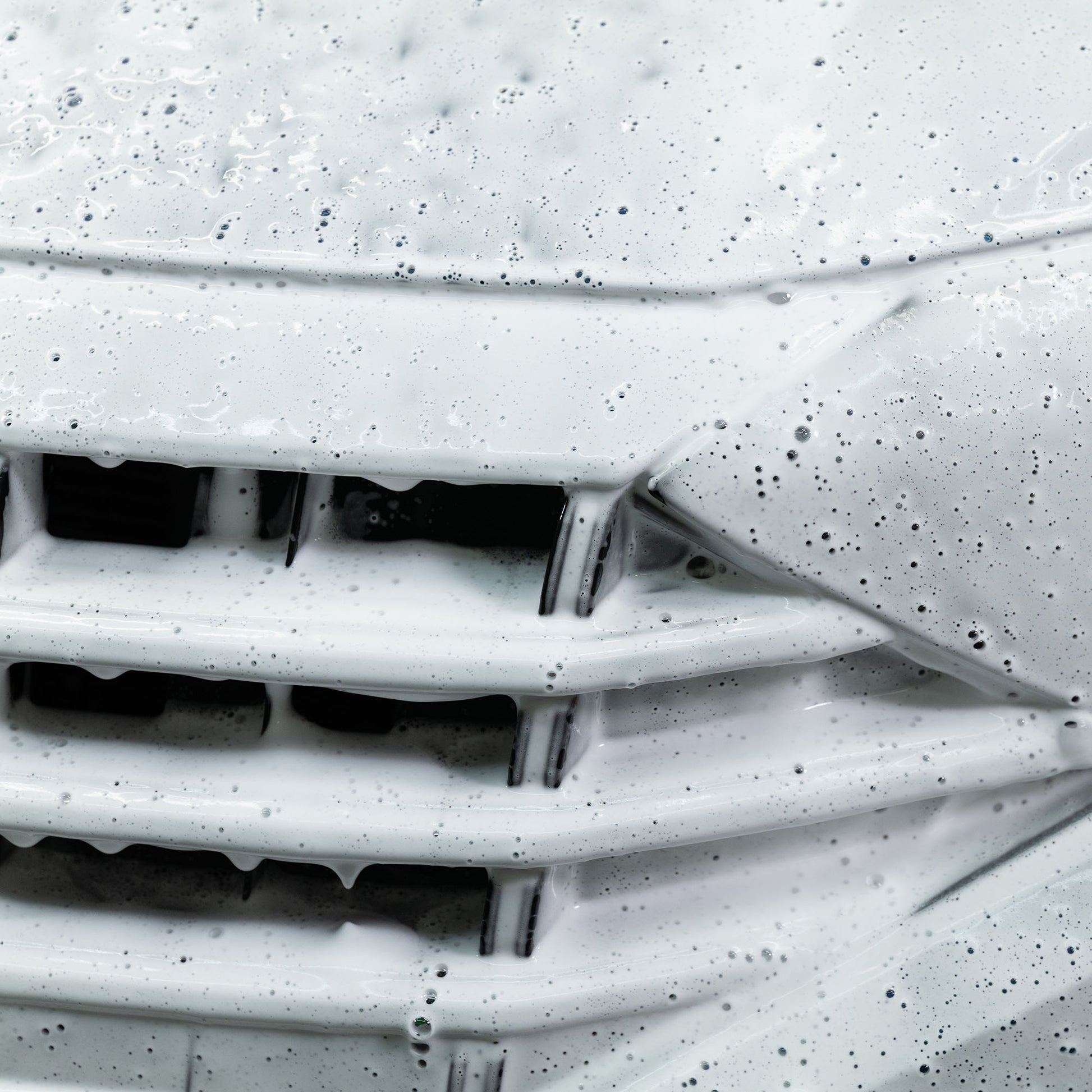 Car grill covered in thick, cleansing white foam. Car detailing.
