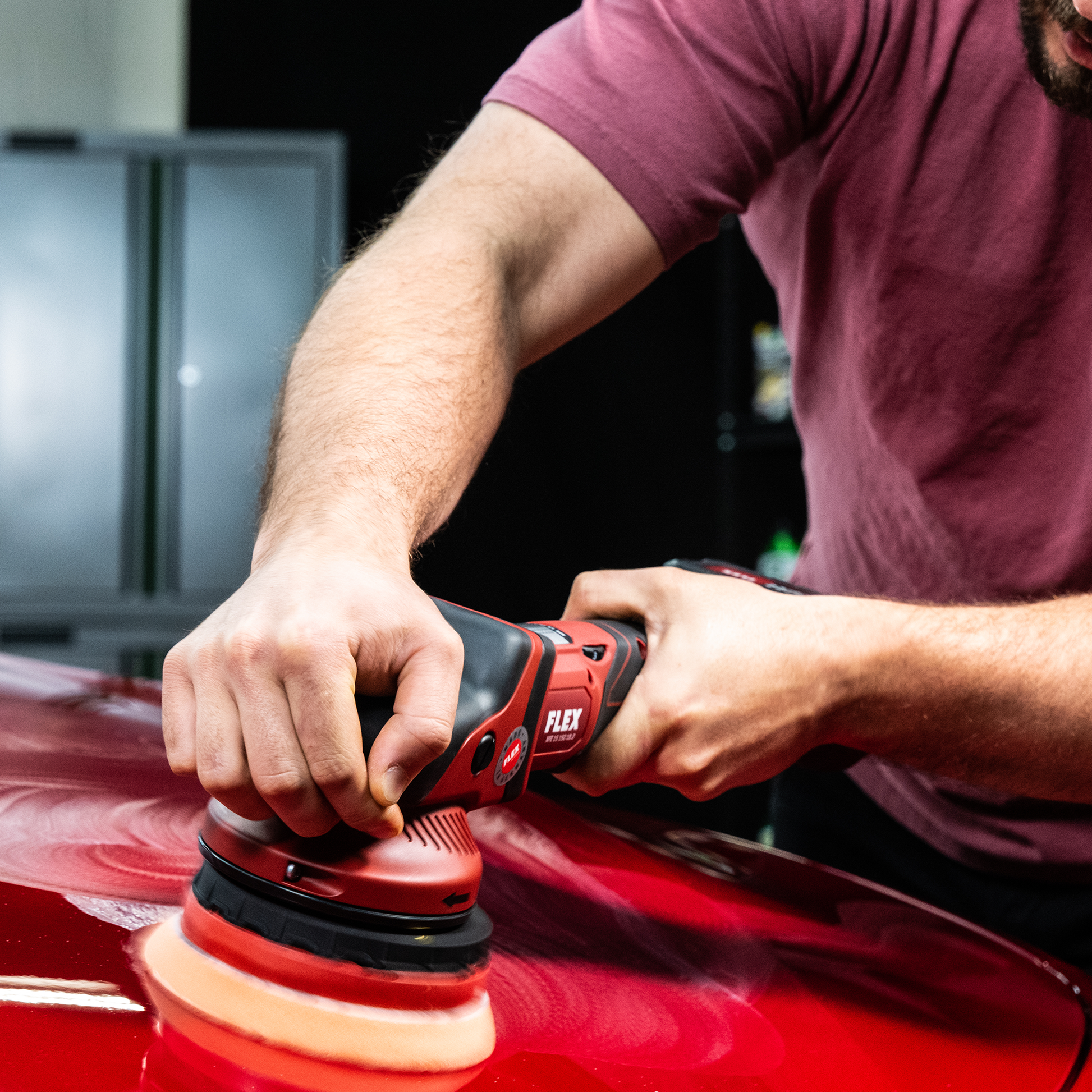 Red car paint correction with a Flex power tool, leaving swirl marks from the buffing compound. Car detailing.