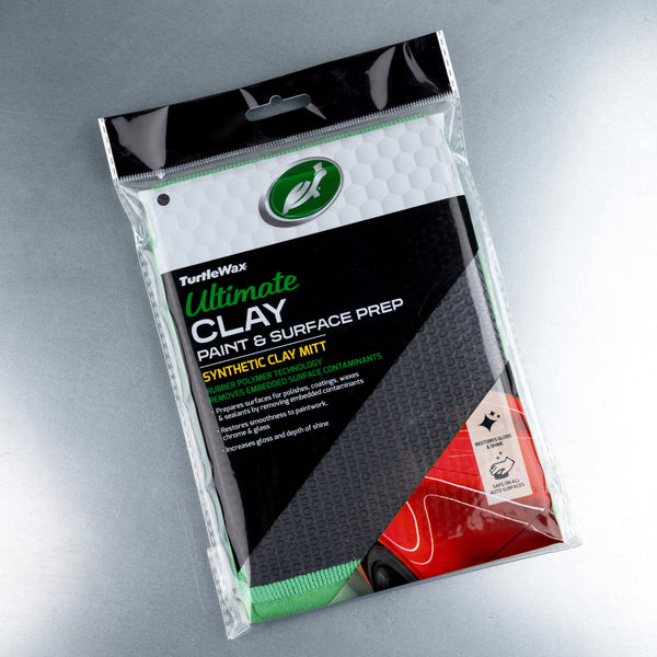 Ultimate Clay Mitt placed on metal car surface, illustrating intended application area for automotive detailing.