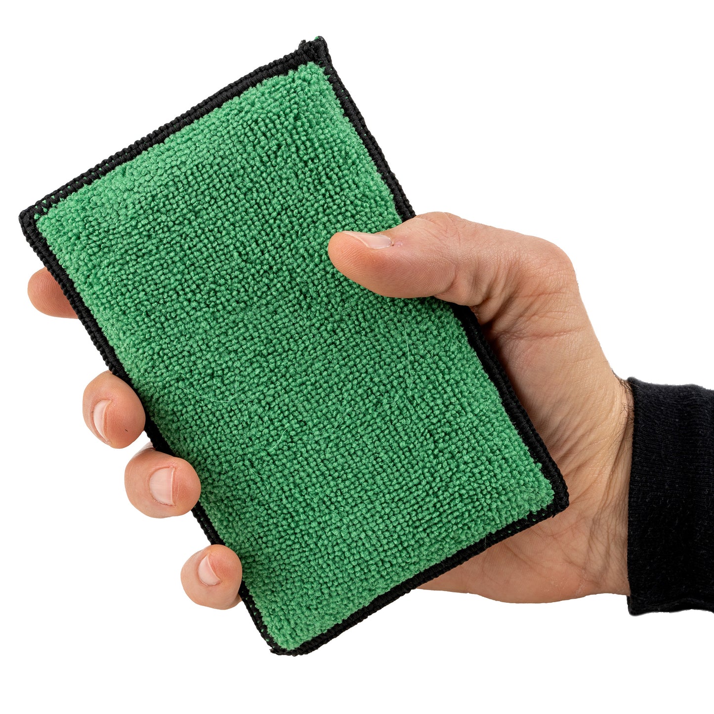 Hand holds a green, soft-textured interior cleaning pad with black edging, ready for car care.