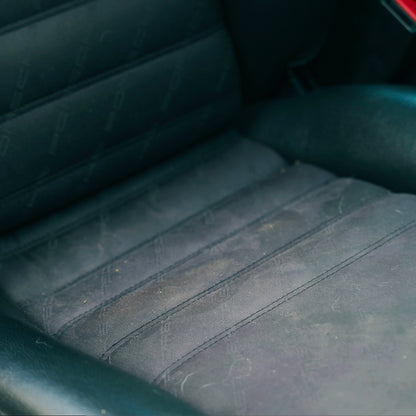 Close-up of a lightly soiled, dark, patterned cloth car seat interior. Showing the detail of the texture and stitching.