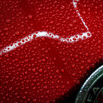 Glossy red car paint with water droplets. A pristine finish and protective layer.