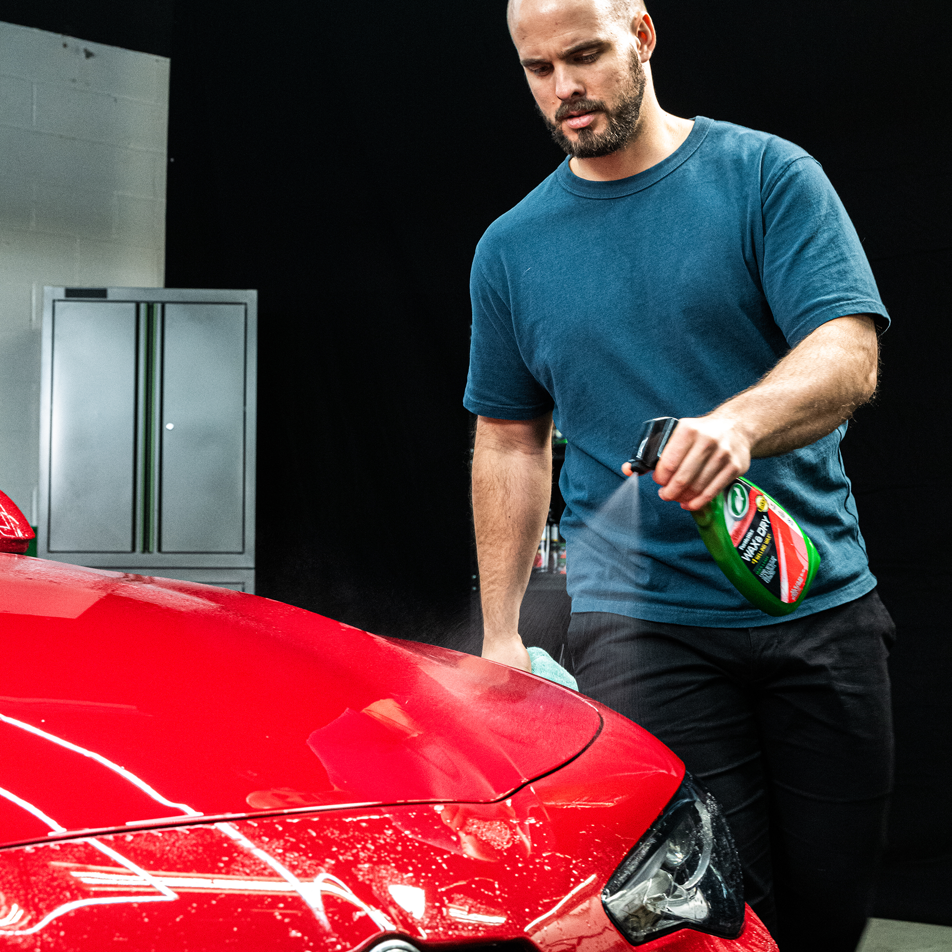 Man detailing red car with Turtle Wax & Dry. Spray bottle application. Car care, cleaning, and polishing.