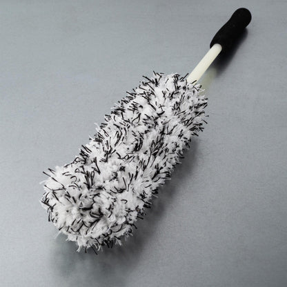 A white and black fuzzy brush with a handle, ideal for car wheel cleaning.
