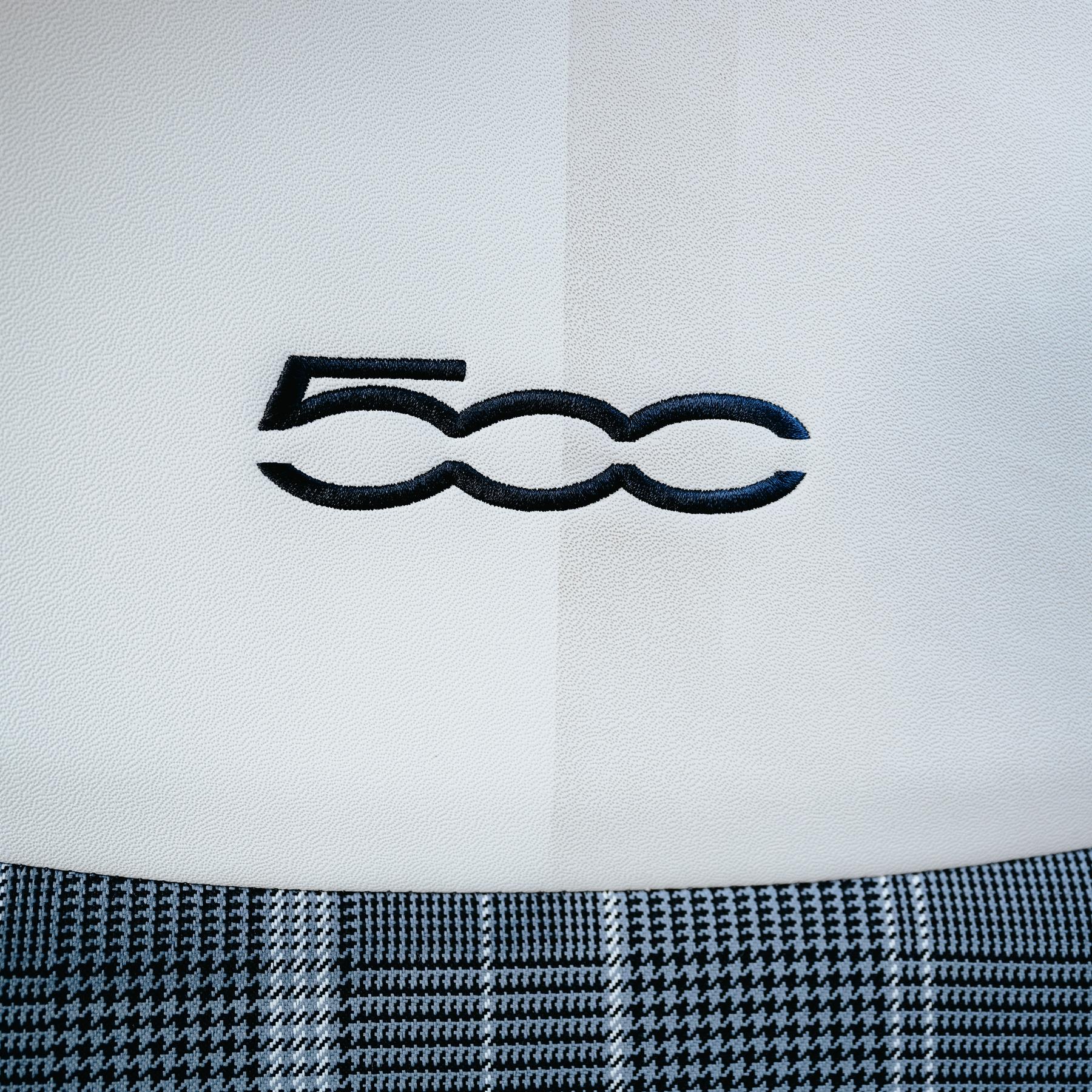 Detail of a car seat with a "500" logo. Shows white leather with a houndstooth pattern. Car detailing.